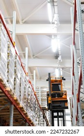 Narrow aisle high-rise stacker. Reach truck with raised cab. High height stacker loader in a industrial warehouse building with rows of racks. - Shutterstock ID 2247232267
