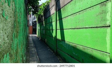 Narrow alley with green and gray walls on either side in Jakrta, Indonesia. - Powered by Shutterstock