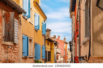 Narrow alley of homes with yellow walls and blue wooden shutters in Roman built town in Croatia. - Powered by Shutterstock