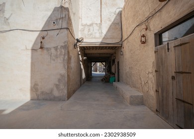 A narrow alleyway lined with tall buildings stretches through a bustling neighborhood in the Al Fahidi market.