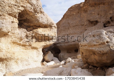 The narrow canyon with high yellow sandstone walls, big stones on its bottom. 