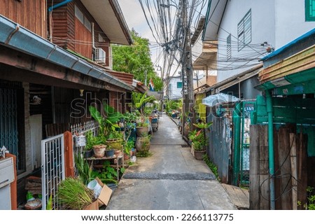 Narrow city street at Bangkok city, Thailand. Small street with houses and green plants around.