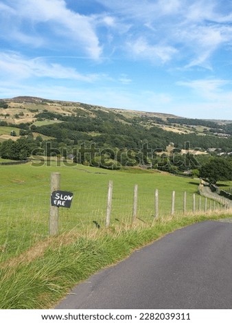 narrow country lane in the calder valley near hebden bridge with home made road sign reading slow ere surrounded by calderdale west yorkshire scenery
