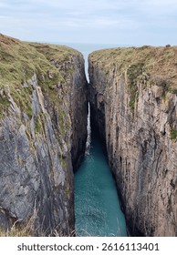 Narrow gap between 2 cliffs with blue sea between - Huntsman's Leap, Pembrokeshire, Wales