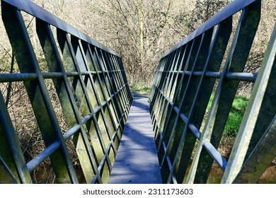 Narrow green iron footbridge over a river in the park - Shutterstock ID 2311173603