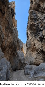 Narrow hiking path passing between high rock walls in a canyon