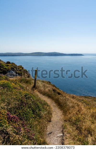 narrow hiking trail and trail marker leading along\
the ridge of the Sheep\'s Head Peninsula with a view of Bantry Bay\
and Mizen Head