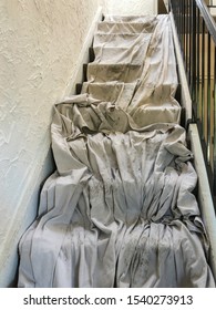 Narrow Interior Stairway With Long Canvas Drop Cloth Laid By Contractor To Protect Carpet During A Roofing Project, For Themes Of Foot Traffic, Wear And Tear, Flexibility