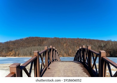 Narrow Metal And Wood Foot Bridge Across River In Autumn