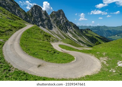 a narrow mountain road meanders down the mountain into the Grosswalsertal, alongside stony mountains over steep flower-strewn meadows in Vorarlberg, Austria