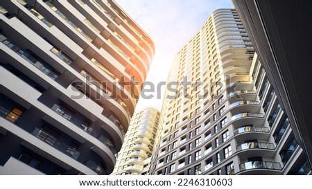 The narrow passage between modern residential buildings. Walls of high-rise apartment buildings and a narrow strip of sky between them. Modern urban living districts. Bottom view.
