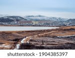 A narrow path that goes into the distance to the Arctic village located between the polar hills. Arctic village Lodeynoye on the shore of the Barents sea.
