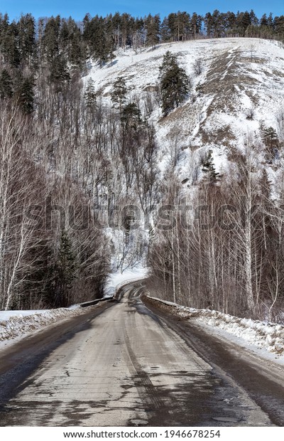 A narrow road\
through a snowy winter\
forest.