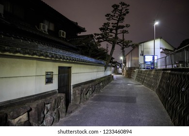 Narrow street curves by traditional Japanese homes at night - Powered by Shutterstock