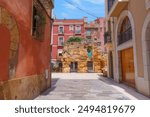 Narrow street featuring colorful buildings and ancient stone walls in Tarragona, Spain