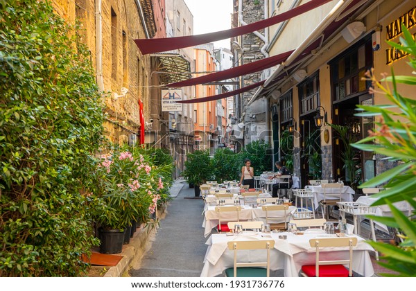 A narrow street half lined with restaurant\
tables. Summer area of the restaurant on a narrow street. Turkey ,\
Istanbul - 21.07.2020