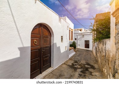Narrow street in Lindos town on Rhodes island, Dodecanese, Greece. Beautiful scenic Lindos old ancient white houses with flowers. Famous tourist destination in South Europe. Lindos, Rhodes, Greece. - Shutterstock ID 2199743831