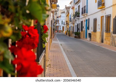 Narrow streets of a Mediterranean village, with balconies and windows adorned with plants and flowers, on a sunny afternoon. In La Nucia, Alicante (Spain). - Powered by Shutterstock