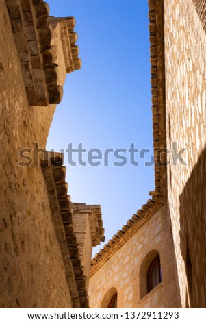 The narrow streets of the old city of Finestrat in Spain, the bottom view of the sky between the stone walls of houses
