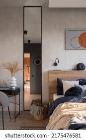 Narrow And Tall Mirror In Black Frame Next To Cozy Bed With Stylish Bedclothes In Modern Bedroom