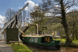 A Narrowboat Passes Through The Lift Bridge At Talybont-on-Usk On The Monmouthshire And Brecon Canal, Brecon Beacons, Wales.