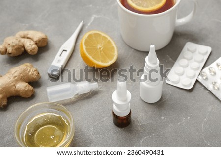 Nasal drops with lemon tea, ginger, honey and pills on grunge background