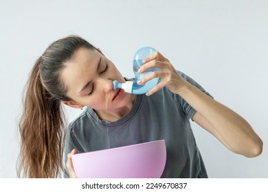 Nasal irrigation. A young girl uses the Neti Pot to treat her runny nose and colds. Nasal lavage, irrigation therapy. - Shutterstock ID 2249670837
