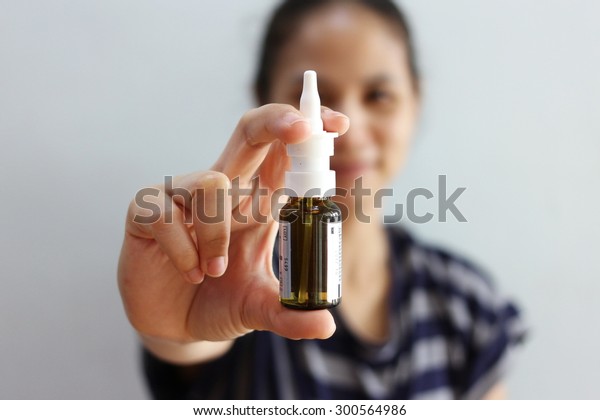  Nasal Spray, Female hand spraying nasal spray\
with blurred background