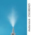 Nasal spray with sprinkled medication over nozzle on light blue background, closeup