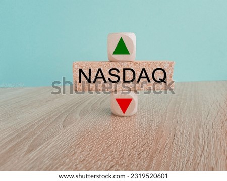 NASDAQ price symbol. A brick block with arrow symbolizing that composite index price are going down or up. Beautiful wooden table blue background. Business and gold price concept. Copy space.