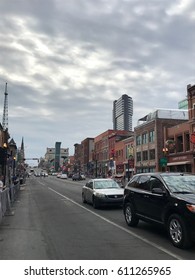 Nashville Tennessee - Circa 2017: Downtown Strip Country Music Row. Bars And Restaurants Line Street With Skyline Background.  