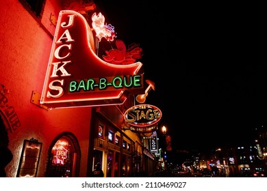 Nashville, Tennessee - January 11, 2022: Neon sign Jacks Bar-b-que on Broadway street, along with other famous signs, lit up at night