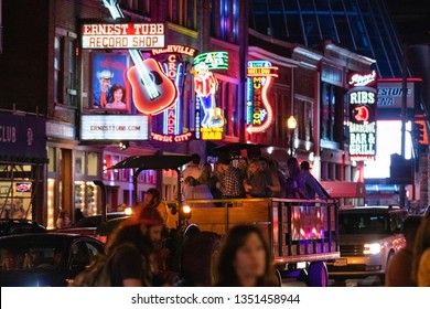 Nashville, Tennessee - March 23, 2019 : Nightlife On Broadway As A Party Bus Passes In Front Of The Bars And Venues Lining The Street. 