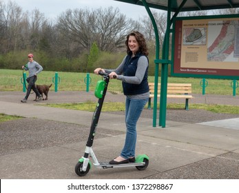 Nashville, Tennessee/USA-April 2019:  Woman On Scooter And Man Walking His Dog Enjoy Shelby Bottoms Greenway And Natural Area .