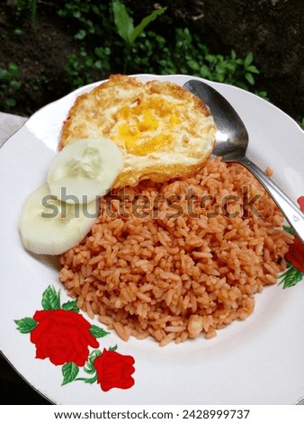 Nasi goreng or fried rice is a food made from rice fried with shallots, garlic, chilli, tomatoes and sweet soy sauce. As a complement add fried eggs and cucumber. Indonesia food.