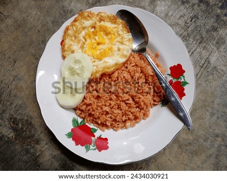 Nasi goreng or fried rice is a food made from rice fried with shallots, garlic, chilli, tomatoes and sweet soy sauce. As a complement add fried eggs and cucumber. Indonesia food. Top view.