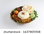 Nasi Uduk Betawi, coconut flavored steamed rice dish from Betawi, Jakarta. Topped with several dishes and served on rattan plate. Isolated white background.