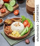 Nasi Uduk, a coconut-flavored steamed rice dish. Topped with several dishes and served on wooden plates. Isolated