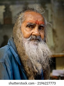 Nathdwara, Rajasthan, India - 4.10.2019 : An Elderly Indian Man With Long Beard And Messy Hair, Wearing Dirty Clothes On Blurred Background