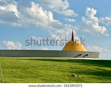 National Corvette museum against a bluebird blue sky with puffy white clouds and bright green grass.