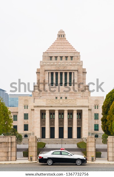 National diet building with a police car during\
in a cloudy day.  The National Diet Building is the building where\
both houses of the National Diet of Japan meet.   It is located\
inTokyo