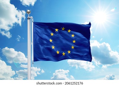National Europe flag waving in the wind, against the blue sky. Wavy flag in the sky with sunbeams.
