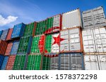 The national flag of Algeria on a large number of metal containers for storing goods stacked in rows on top of each other. Conception of storage of goods by importers, exporters