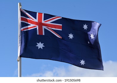 The National Flag Of Australia On A Flagpole Pole Blowing And Flying In The Wind Against Blue Sky. No People. Copy Space