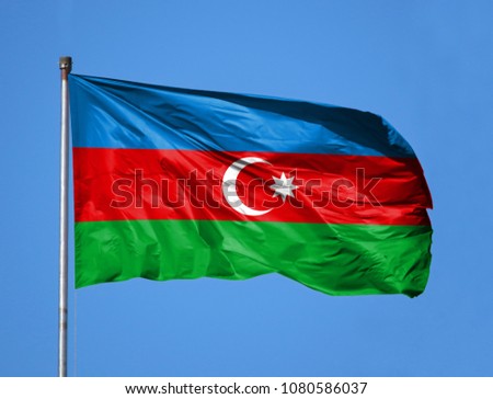 National flag of Azerbaijan on a flagpole in front of blue sky
