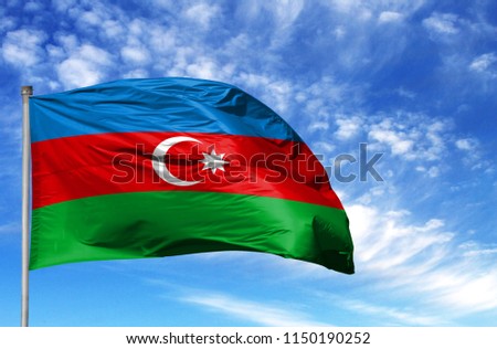 National flag of Azerbaijan on a flagpole in front of blue sky