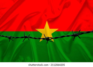 National Flag Of Burkina Faso On Satin, Iron Barbed Wire, Concept Of War, Revolution, An Armed Uprising In The Country, Shootout Of Bandits, Terrorist Attack, A Redistribution Of Power