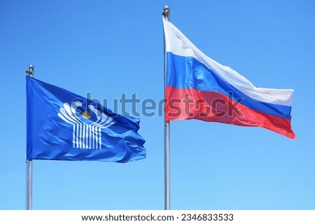 National flag of CIS on a flagpole. CIS flag and flag of Russia on the background of the sky. Flags of the Commonwealth of Independent States (CIS) organization waving in the wind against blue sky