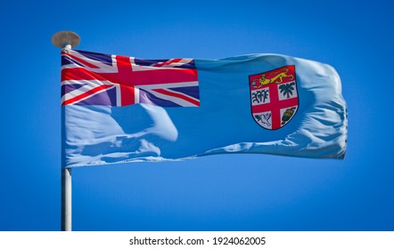 The national flag of Fiji. Known as the Kuila Mai Viti flag. Fijian flag blowing in strong wind against a pure blue sky. Symbol of national patriotism
