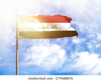 National flag of Iraq on a flagpole in front of blue sky